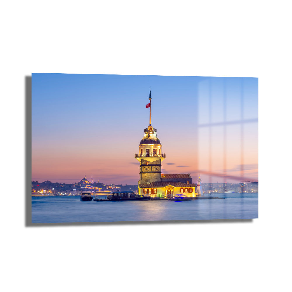 Kız Kulesi'nin Sonsuz Büyüsü: Gün Batımı Işığında İstanbul Cam Tablosu, İstanbul Boğazı'ndaki Kız Kulesi'nin gün batımı ışıkları altında, turuncu ve mor tonlardaki gökyüzüyle büyüleyici manzarasını gösteren dekoratif cam duvar sanatı.