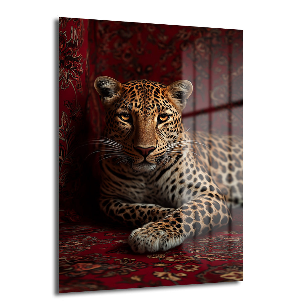 Kırmızı ve bordo tonlarında desenli bir halı üzerinde uzanmış, altın gözlü asil bir leopar portresi içeren dekoratif temperli cam tablo, modern salonlar için güçlü bir duvar dekorasyonu.