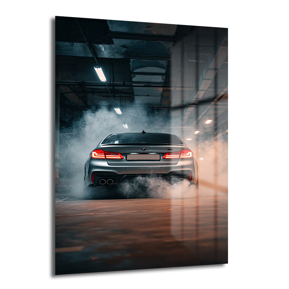 Arka planda dumanlar içinde, kırmızı stop lambaları yanan gümüş renkli bir BMW M5 otomobilin yer aldığı temperli cam tablo, modern ofis veya salon duvar dekorasyonu için ideal.