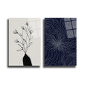 Vazoda çizgisel siyah çiçek çizimi ve lacivert zeminde beyaz soyut dalgalı desenler içeren iki parçalı modern cam tablo seti.