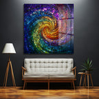 Koyu gri bir duvarda asılı, parlak ve canlı renkte mozaik spiral desenine sahip büyük bir cam tablo. Tablo, gökkuşağı renklerinde küçük cam parçacıklarının spiral şeklinde dizilmesiyle oluşan dinamik bir girdap deseni sergiliyor. Tablonun altında bej renkli, modern bir iki kişilik kanepe yer alıyor. Solunda ahşap ayaklı beyaz bir lamba, sağında ise yeşil bitkili ahşap bir sehpa bulunuyor. Zemin parlak ahşap parkeden oluşuyor.