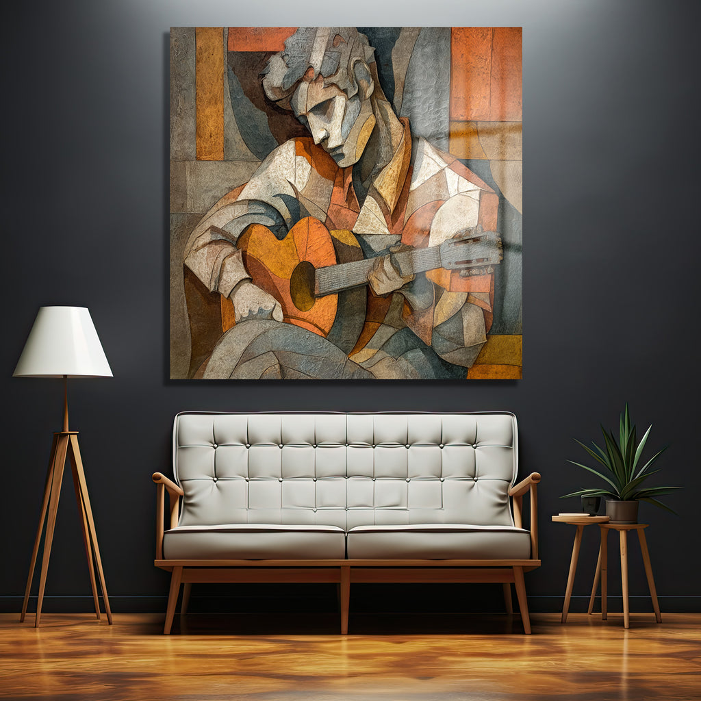 Kübist tarzda, gitar çalan bir müzisyenin portresi şeklinde cam tablo, turuncu, kahverengi ve gri tonlarında geometrik şekillerle oluşturulmuş, modern bir iç mekanda sergileniyor.