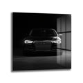 Karanlık bir ortamda, parlak farları açık, önden çekilmiş siyah renkli modern Audi otomobilin cam tablo görünümü.