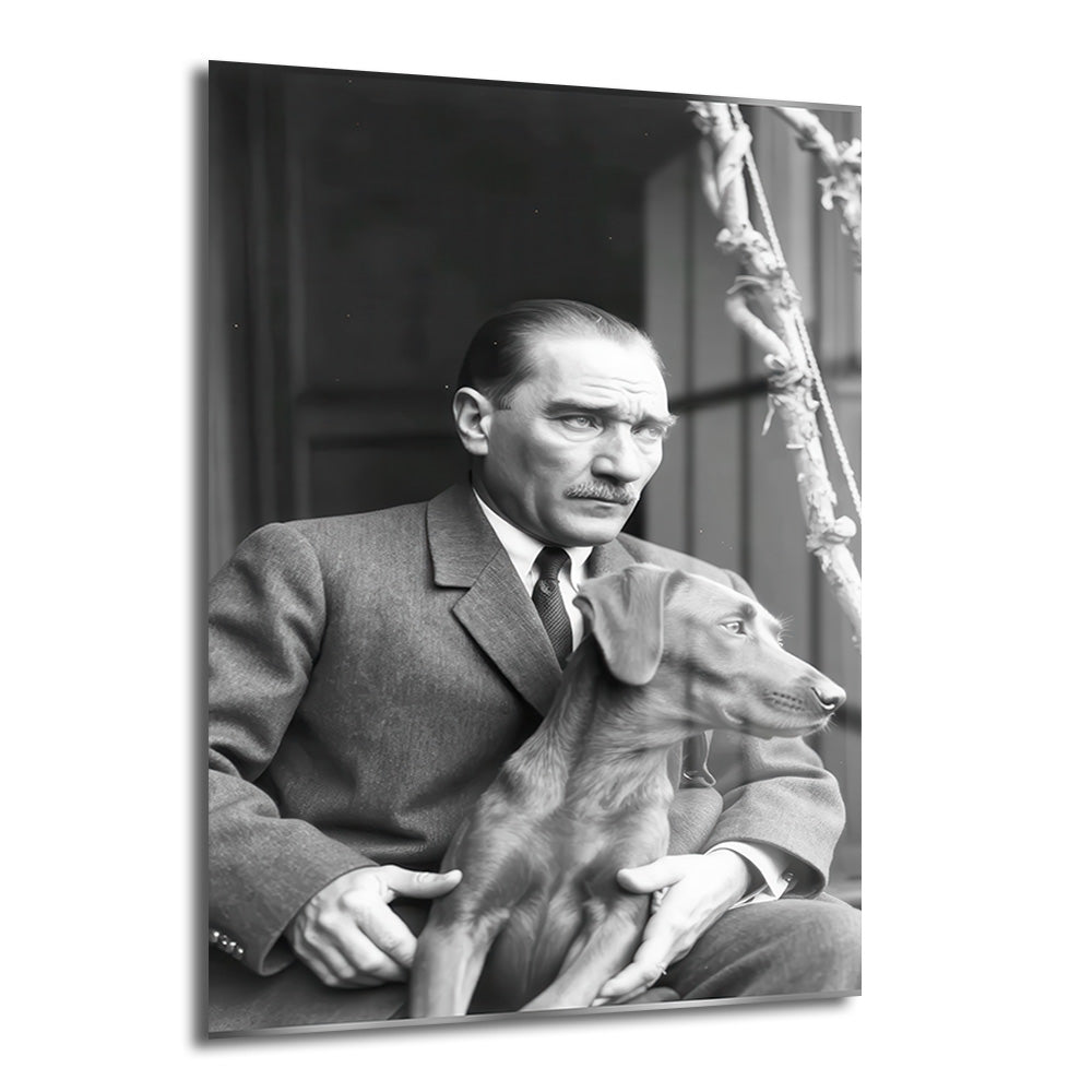 Siyah beyaz bir fotoğraf karesinde, takım elbiseli Mustafa Kemal Atatürk'ün kucağında oturan Foks isimli köpeğiyle birlikte dışarıya doğru baktığı, düşünceli bir anı gösteren cam tablo.