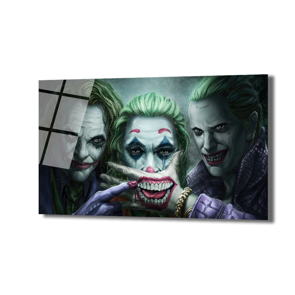 Üç farklı Joker karakterinin bir arada tasvir edildiği cam tablo. Solda Heath Ledger'ın Joker'i, ortada Joaquin Phoenix'in gözleri yaşlı Joker'i ve elinde büyük, kırmızı bir gülümseme tutan bir el, sağda ise Jared Leto'nun Joker'i yer alıyor. Yeşil saçlar, mor ve gri tonlar hakim.
