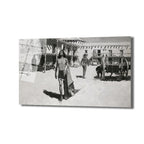 Monokrom tonlarda, eski bir köy veya kasaba meydanında yürüyen bir adamı ve arka planda tarihi binaları, diğer insanları ve bir at arabasını gösteren sanatsal bir tablo.