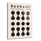 Açık krem rengi arka plan üzerinde siyah renkte 'BAUHAUS Ausstellung 1919' yazısı ve alt alta sıralanmış geometrik, minimalist şekillerden oluşan bir cam tablo. Şekiller arasında üstte ve altta 'dumbbell' benzeri formlar, ortada ise düz siyah daireler bulunmaktadır.