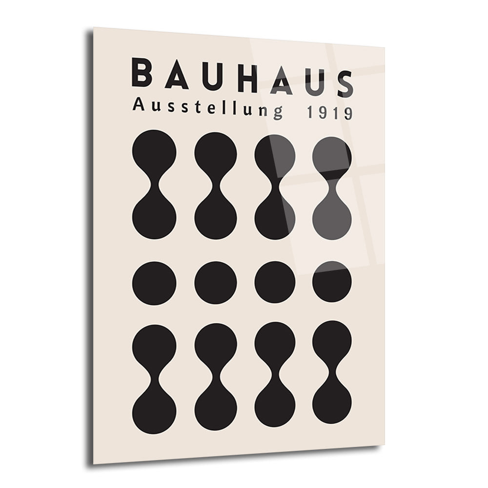Açık krem rengi arka plan üzerinde siyah renkte 'BAUHAUS Ausstellung 1919' yazısı ve alt alta sıralanmış geometrik, minimalist şekillerden oluşan bir cam tablo. Şekiller arasında üstte ve altta 'dumbbell' benzeri formlar, ortada ise düz siyah daireler bulunmaktadır.