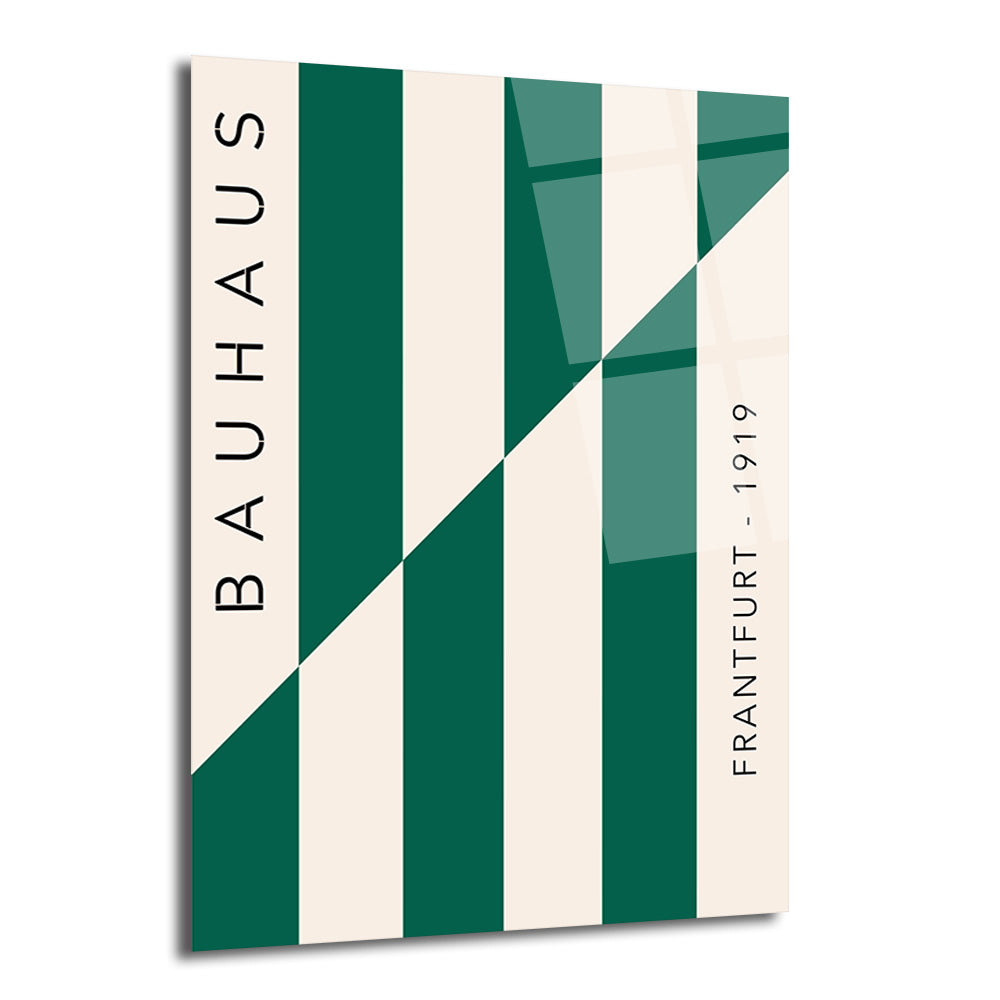 Krem ve koyu yeşil dikey şeritlerin çapraz bir çizgiyle kesiştiği, solunda 'BAUHAUS', sağında 'FRANTFURT - 1919' yazan minimalist ve geometrik cam tablo.