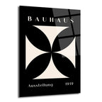 Siyah zemin üzerine bej renkli, dört kollu, geometrik haç deseni bulunan, üstte 'BAUHAUS' ve altta 'Ausstellung 1919' yazılı minimalist cam tablo.