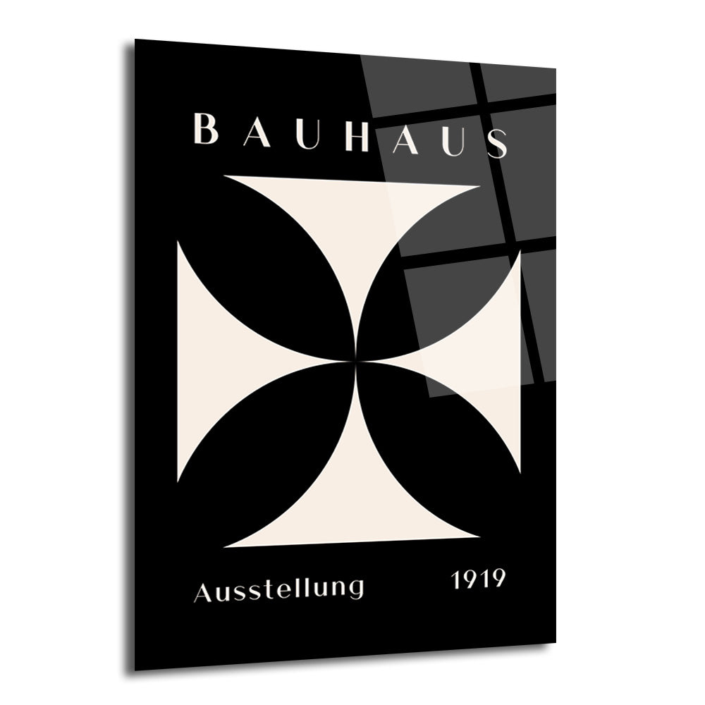 Siyah zemin üzerine bej renkli, dört kollu, geometrik haç deseni bulunan, üstte 'BAUHAUS' ve altta 'Ausstellung 1919' yazılı minimalist cam tablo.