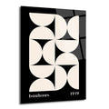 Siyah zemin üzerinde bej renkli yarım dairelerin simetrik ve geometrik desen oluşturduğu, alt kısmında 'bauhaus' ve '1919' yazan minimalist bir cam tablo.
