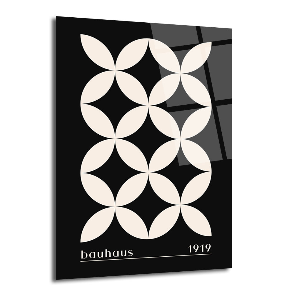 Siyah zemin üzerinde bej renkli, birbirine kenetlenmiş dairesel formlardan oluşan geometrik desenli, Bauhaus 1919 yazılı modern cam tablo.