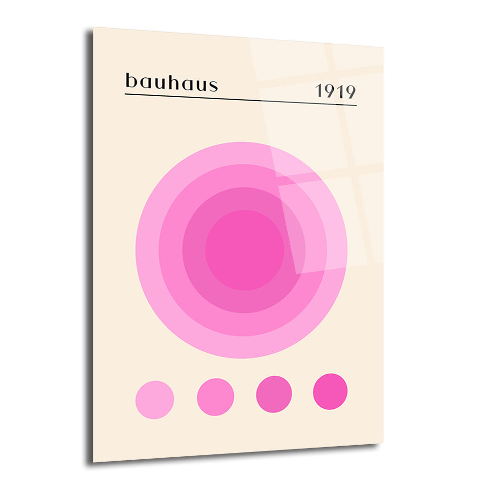 Krem rengi arka plan üzerinde, ortada iç içe geçmiş pembe tonlarında dairelerin bulunduğu, üst kısmında 'bauhaus' ve '1919' yazan, alt kısmında ise dört küçük pembe dairenin sıralandığı modern sanat tarzında bir cam tablo.