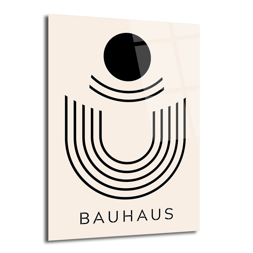Açık bej bir zeminde siyah bir daire ve altında eşit aralıklarla sıralanmış, U şeklinde geometrik çizgilerle oluşturulmuş minimalist bir tasarımın yer aldığı, altında 'BAUHAUS' yazan parlak cam tablo.