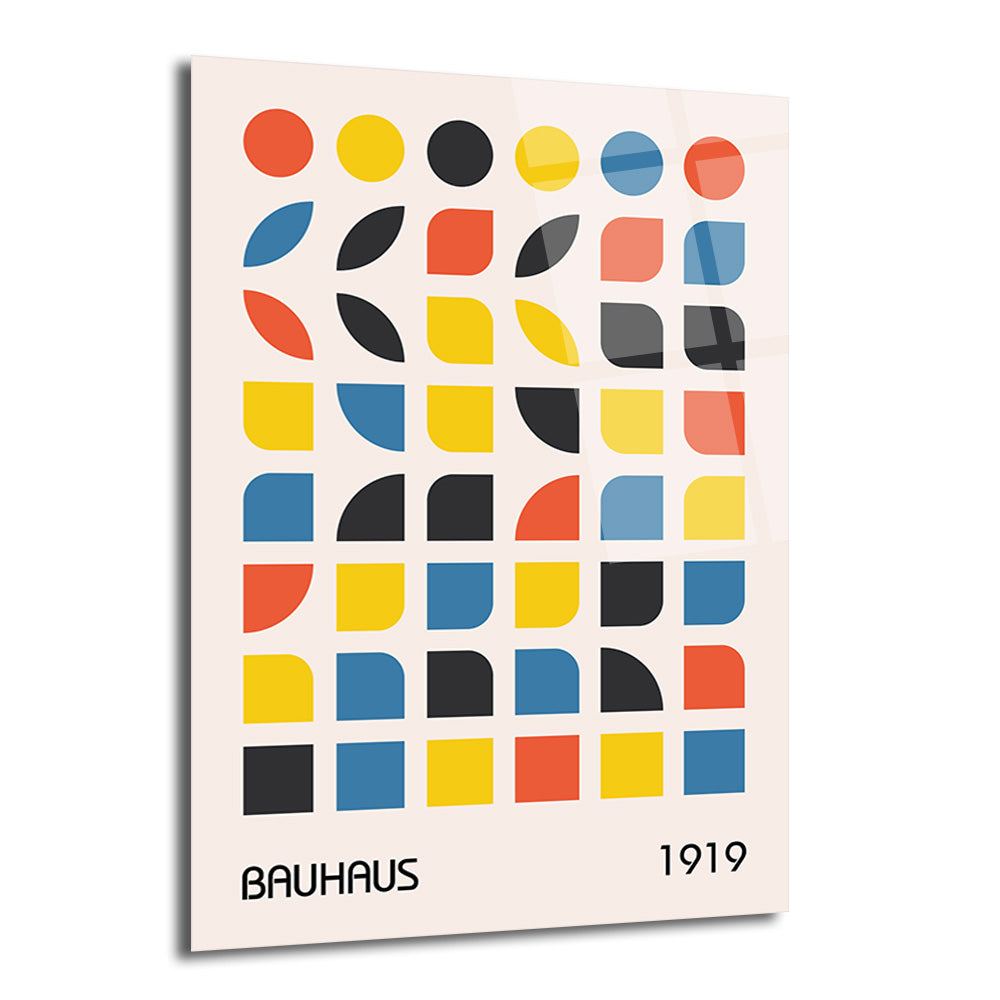 Krem rengi zeminde kırmızı, sarı, siyah ve mavi renklerde Bauhaus tarzı geometrik şekillerden (tam daireler, yarım daireler, çeyrek daireler ve yaprak benzeri formlar) oluşan, 'BAUHAUS' ve '1919' yazılarının yer aldığı parlak bir cam tablo.