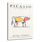Açık krem renkli arka plan üzerinde, Picasso'nun Le Taureau adlı eserinden esinlenilmiş, soyut ve minimalist bir boğa çizimi içeren cam tablo. Boğa figürü siyah ince çizgilerle ana hatları belirlenmiş, içinde kırmızı, sarı, mavi gibi canlı renk blokları barındırıyor. Üstte 'PICASSO LE TAUREAU', altta 'MUSEE D'ORSAY RUE DE LA LEGION D'HONNEUR . PARIS' yazıları bulunuyor.