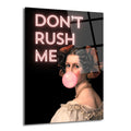 Siyah arka planda, pembe neon harflerle "DON'T RUSH ME" yazısı ve pembe sakız balonu üfleyen, klasik giysili, inci kolyeli bir kadın portresi.