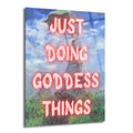 Monet tarzı bir resmin üzerine pembe, parlayan harflerle "JUST DOING GODDESS THINGS" yazısının eklendiği, elinde şemsiye tutan bir kadını ve arkasında mavi gökyüzü ile yeşil çimenleri gösteren modern cam tablo.