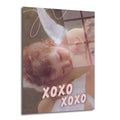 Kanatlı bir meleğin uyuduğu klasik tarzda resmedilmiş bir tablonun üzerine pembe renkte 'XOXO XOXO' yazısının eklendiği, pastel tonlarda bir cam tablo. Arka planda yumuşak kahverengi ve krem tonları, meleğin kıvırcık saçları ve kanatları belirgin.