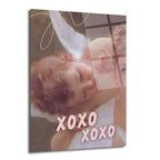 Kanatlı bir meleğin uyuduğu klasik tarzda resmedilmiş bir tablonun üzerine pembe renkte 'XOXO XOXO' yazısının eklendiği, pastel tonlarda bir cam tablo. Arka planda yumuşak kahverengi ve krem tonları, meleğin kıvırcık saçları ve kanatları belirgin.