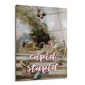 Klasik bahçe sahnesinde iki çerubun yer aldığı, üzerine pembe renkte 'cupid stupid' yazısı eklenmiş modern ve esprili cam tablo.