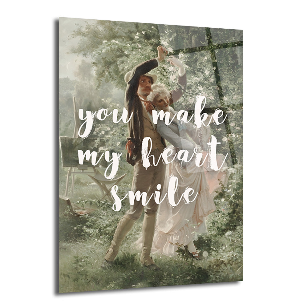 Yeşil ve beyaz çiçekli bir bahçede dans eden klasik giyimli romantik bir çiftin resmedildiği, üzerinde 'You Make My Heart Smile' yazılı Glazella cam tablo.