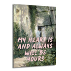 Üzerinde 'MY HEART IS AND ALWAYS WILL BE YOURS' yazan pembe bir mesajın bulunduğu, yemyeşil bitkilerle çevrili eski bir evde duran beyaz elbiseli bir kadını gösteren romantik ve sanatsal cam tablo.