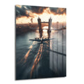Dramatik Londra Uçuşu: Tower Bridge ve Gün Batımı Cam Tablo, Tower Bridge üzerinde gün batımında süzülen vintage bir uçağı ve Thames Nehri'nin kızıl yansımalarını gösteren modern bir duvar dekoru.